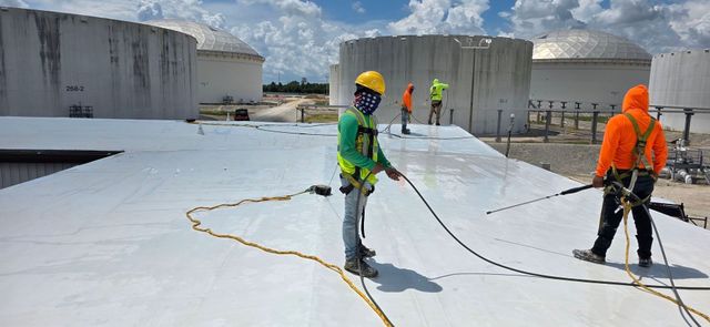 Longhorn crew spray-applying a reflective coating across a flat commercial roof